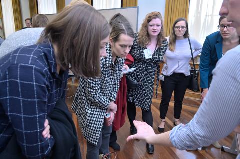 Several people lean over to view a substance held in another person's palm. 