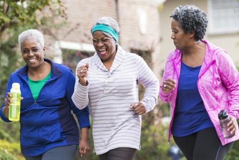 Three smiling women, holding water bottles, on a fitness walk
