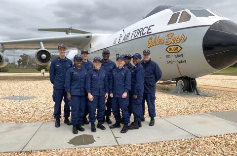 Several members stand in front of a plane