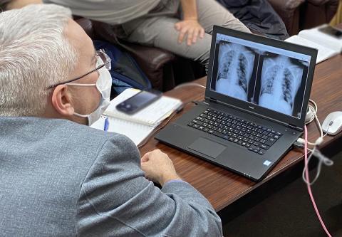 Childs, wearing a mask, looks at x-rays on a laptop.
