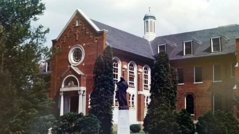 Historic image of the Cloister building with statuette in front