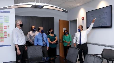 With touring group looking on, Memarzadeh gestures toward wall.