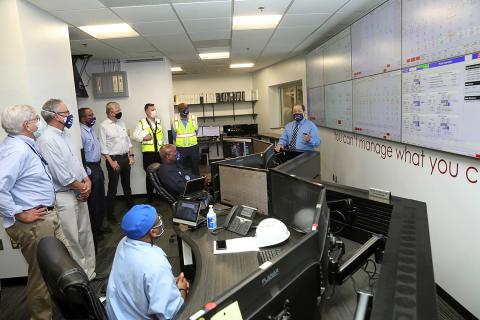 Touring group stands facing a wall of computer screens, as a CUP staff member describes the view. 