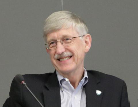 A smiling Collins seated by microphone