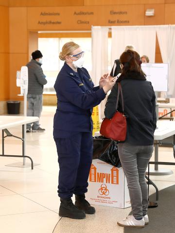 A PHS member takes the temperature of an employee entering the CC.