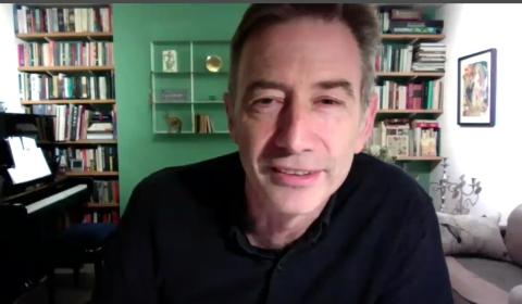 Parker speaks on videocast from his living room, with piano behind him