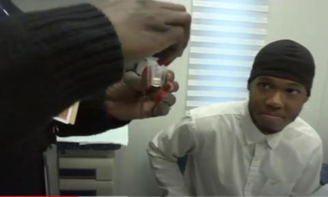 A man looks on as a nurse holds a specimen cup.