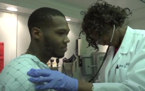 An investigator holds a stethoscope to a man's chest in the MRV.
