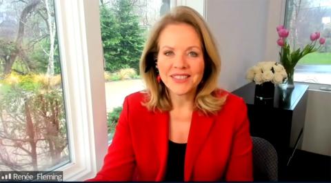 A smiling Renee Fleming wearing a red blazer speaks from her home.