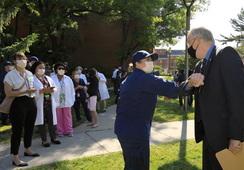 Collins elbow bumps a Public Health Service Member while onlookers watch
