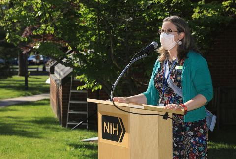 Dr. McCormick-Ell speaks at a podium while wearing a mask