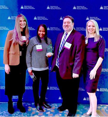 Group photo of Optimize NIH IT security staff in front of royal blue backdrop