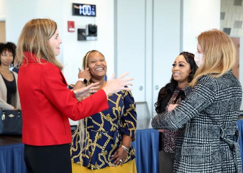 Four women talk informally before start of event.
