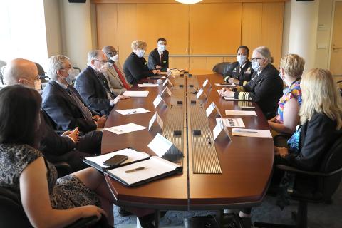 Masked people sit around a conference table