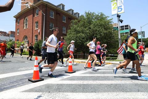 Several rows of runners navigate around orange cones.