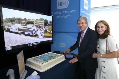 Roy cuts cake with Abby next to him. 