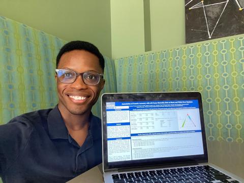 Crump smiles next a laptop. A digital copy of his poster is on the laptop's screen