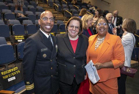 Three attendees pose together in the auditorium.