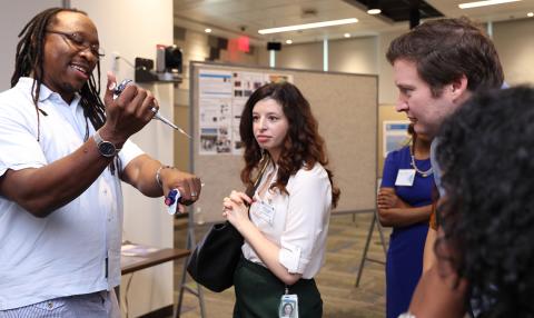 Platt holds a pipette while staffers look on.