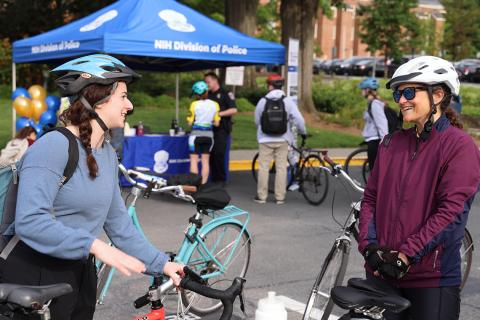Two cyclists stand with their bikes discussing their rides in