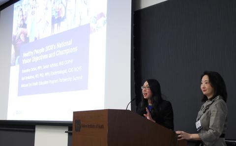 Devina Fan speaks into mic at podium as Ochiai looks on.