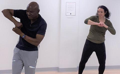 Bacanamwo and Burgess stand in gym dancing, rolling their arms