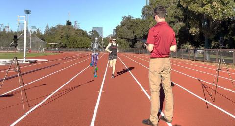 A researcher uses a camera to record someone running on a track