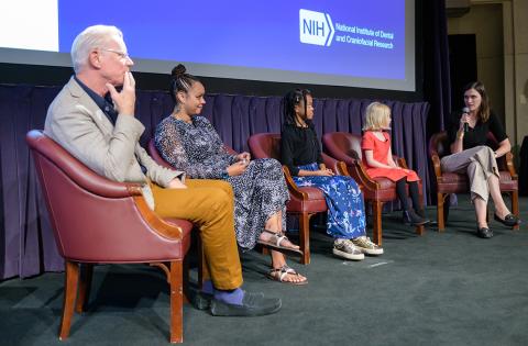 Panelists sit on stage. Boyce is talking into mic as others listen.