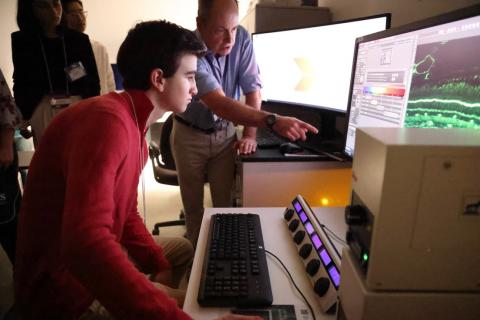 Dr. Fariss directs Leschinsky as he uses a computer to work a microscope