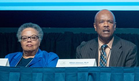 Frasier and Johnson sit at conference table.