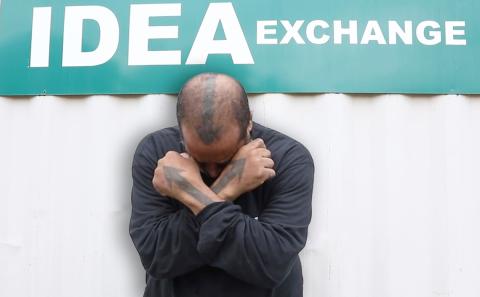 Archer bows head, with arms crossed in an X across his body, with IDEA Exchange displayed 