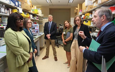 Three congresswomen gather around as Lowy talks with them, and Widemann and Shern look on