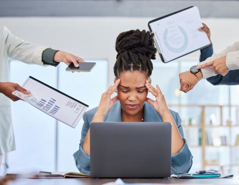 A woman holds her head in front of a laptop screen