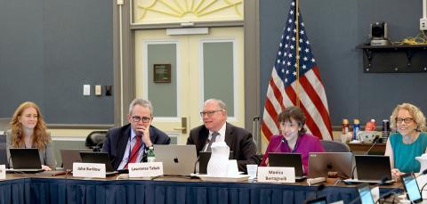 several people seated at a conference table, smiling