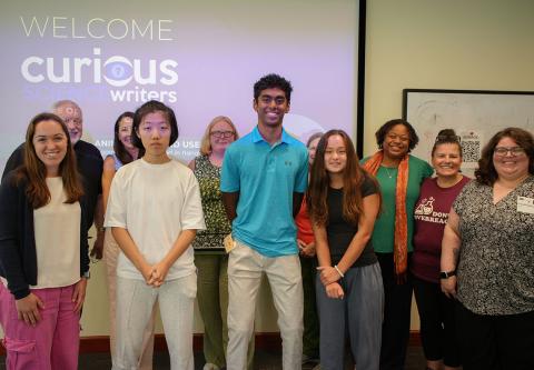 cSw students and presenters pose for a group photo. Behind them, a projector screen reads "Welcome Curious Science Writers."