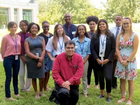A group of students pose outdoors. Dr. Perez-Gonzalez kneels at the forefront of the group.