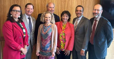 Group poses together smiling, in an OU office
