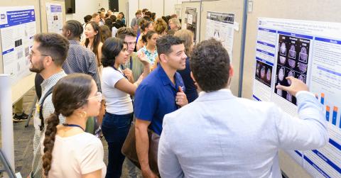 Lots of people gather around several scientific posters.