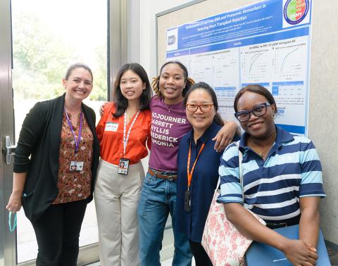 A group of interns and staff from NHLBI pose by a poster.