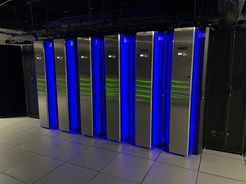 A row of tall silver coolers, with gaps between them where blue light shines from within.