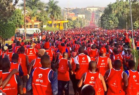 Hundreds of people in red tank tops flood the streets of Kampala for a run.