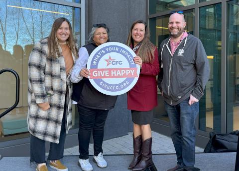 Group stands together holding Give Happy sign.