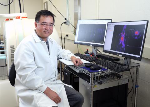 Dr. Ying Ma wearing white lab coat sits in front of computer workstation