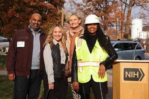 Four ceremony attendees pose for a photo next to the podium.