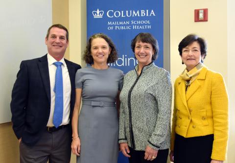 Three women and one man smile with Columbia Mailman School of Public Health logo behind them.