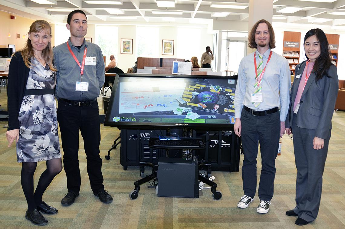 Group stands beside data visualization screen in the NIH Library.