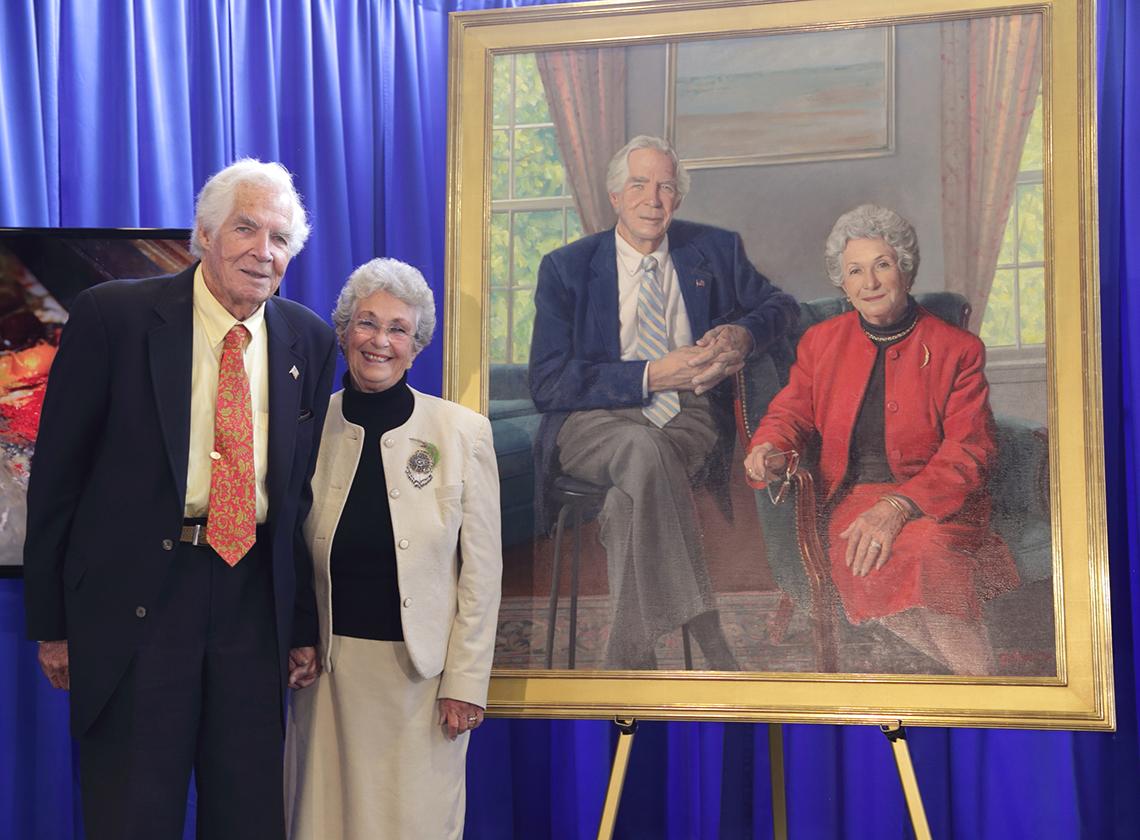 Dr. and Mrs. Lindberg stand by a portrait of themselves.
