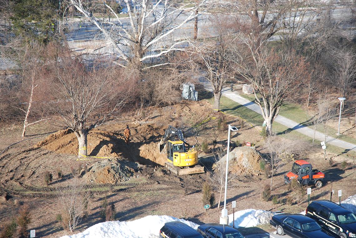 Workmen dig a hole around the ruptured pipe.