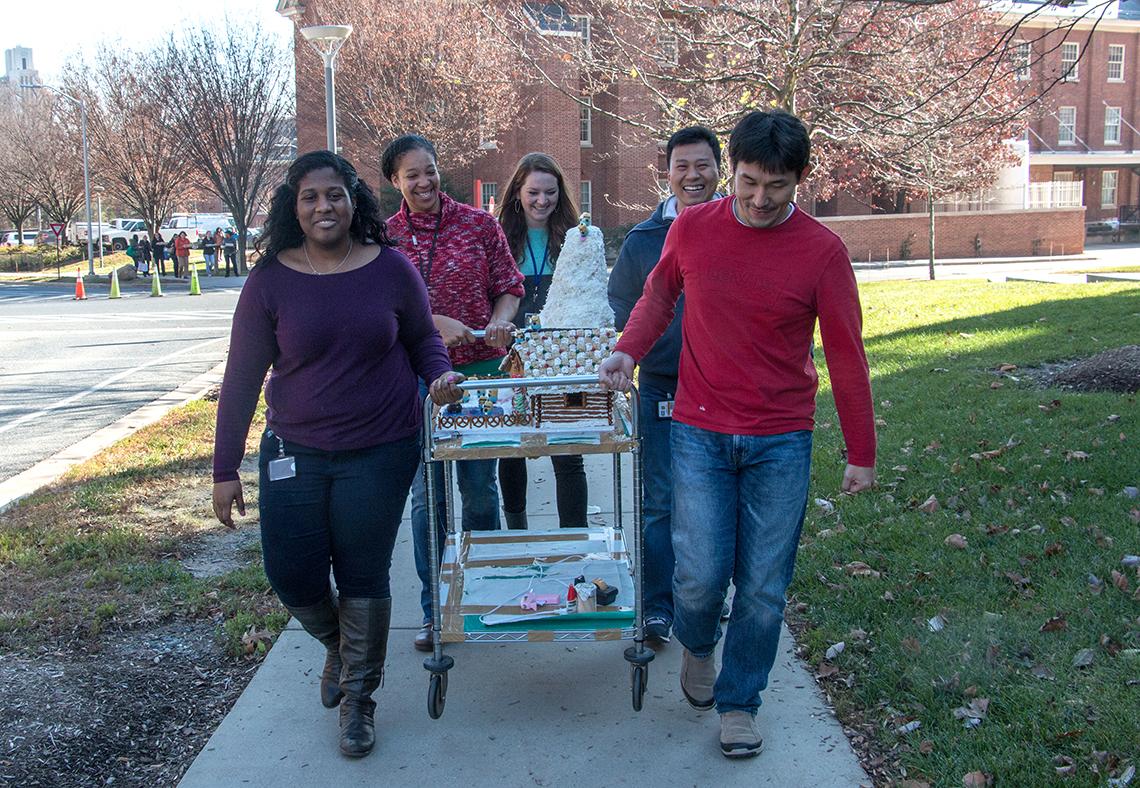 Group carries gingerbread house to contest.