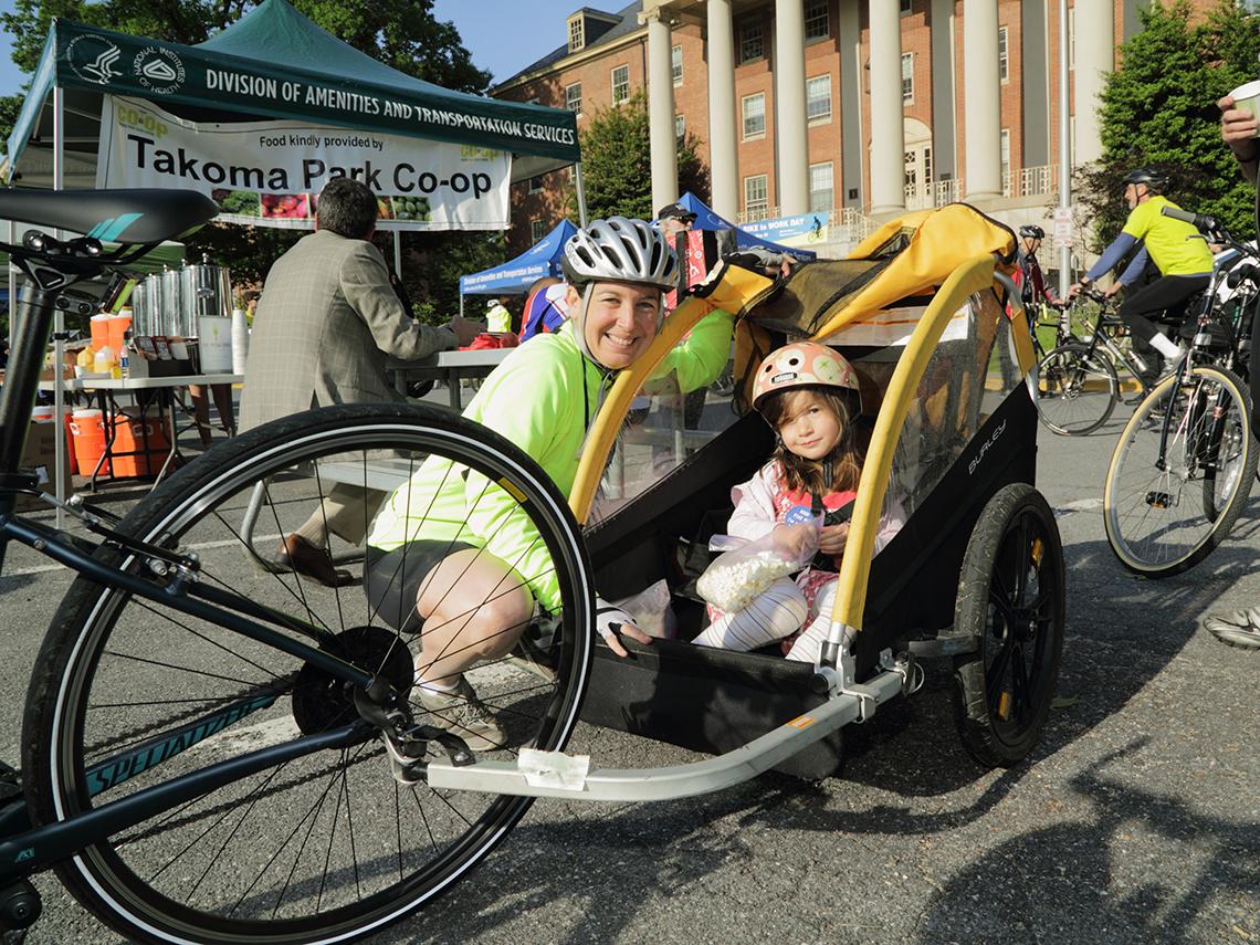 Woman bikes in with a child in tow.